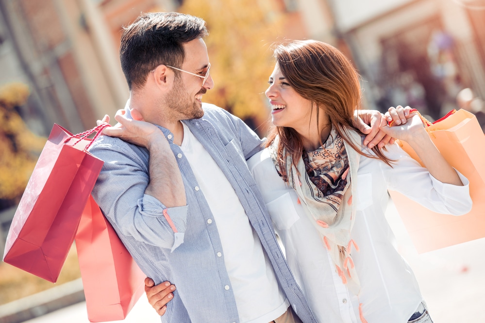 a happy couple carrying shopping bags